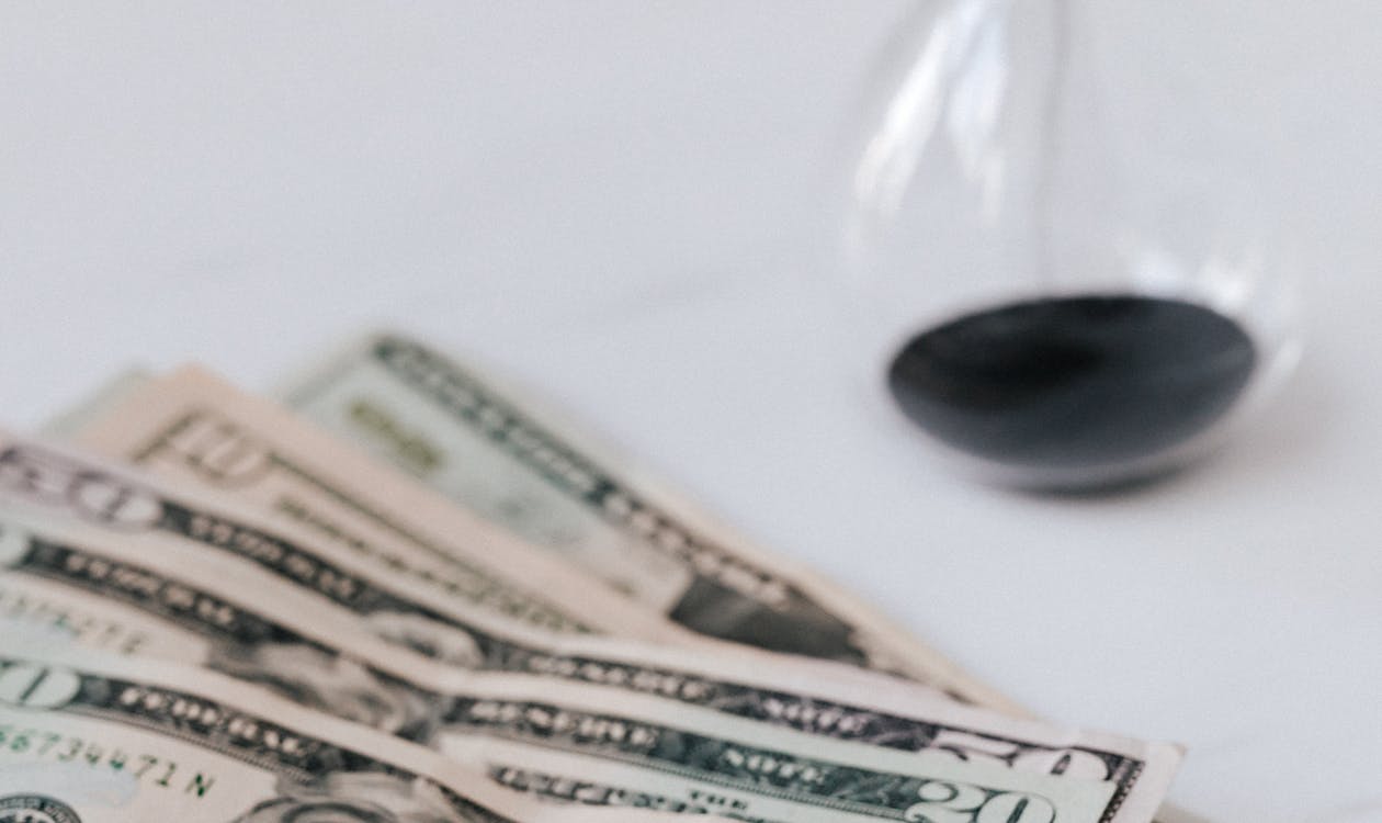 Hourglass beside a stack of US dollar bills, illustrating time and money in software development